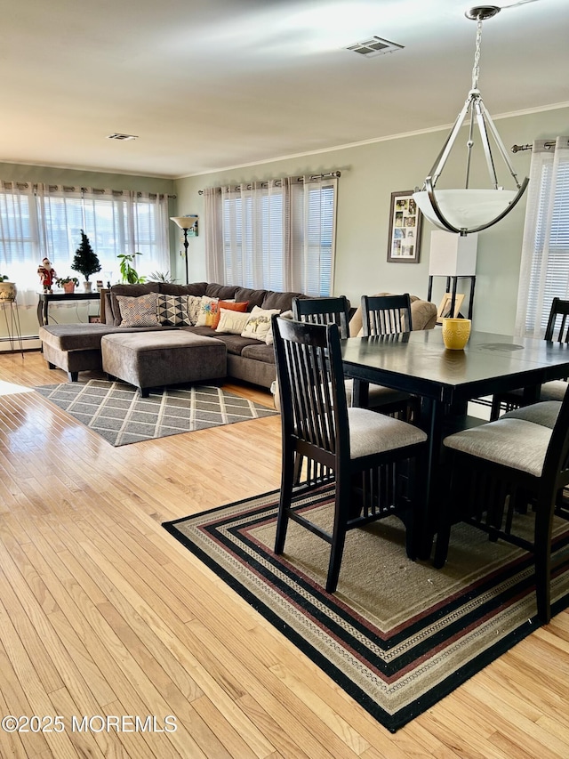 dining room featuring a baseboard heating unit, crown molding, and light hardwood / wood-style floors