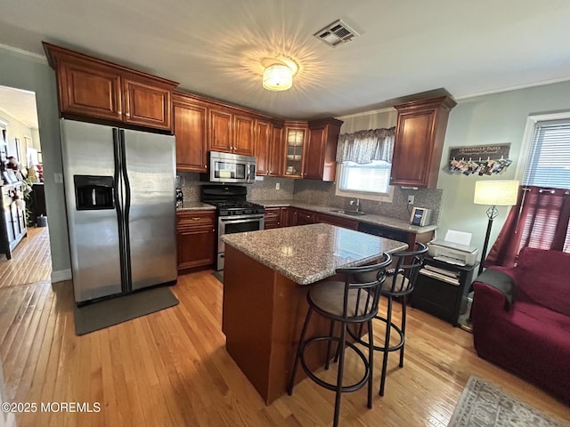 kitchen with a center island, a kitchen bar, sink, light wood-type flooring, and appliances with stainless steel finishes