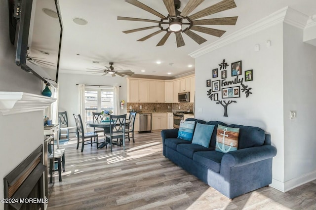 living room featuring a fireplace, light hardwood / wood-style flooring, ceiling fan, and ornamental molding