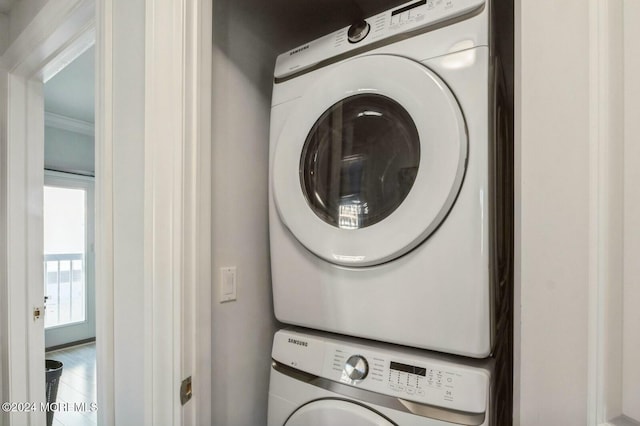 laundry room with crown molding and stacked washing maching and dryer