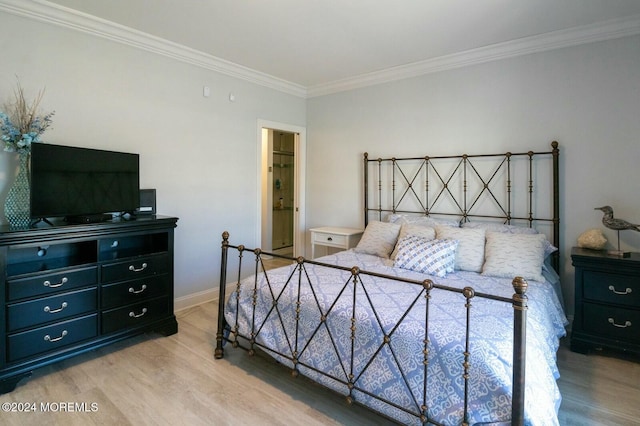 bedroom featuring light hardwood / wood-style floors, crown molding, and connected bathroom