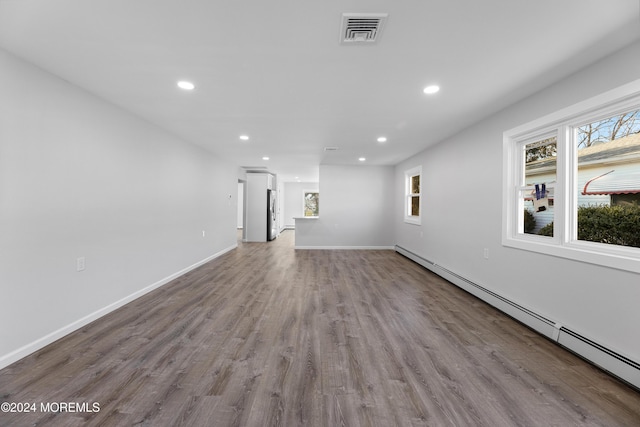 unfurnished living room with a wealth of natural light, light hardwood / wood-style floors, and a baseboard heating unit