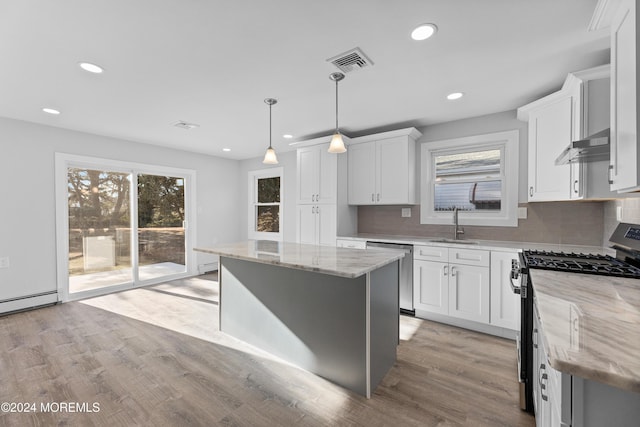 kitchen with a center island, light stone counters, pendant lighting, white cabinets, and appliances with stainless steel finishes