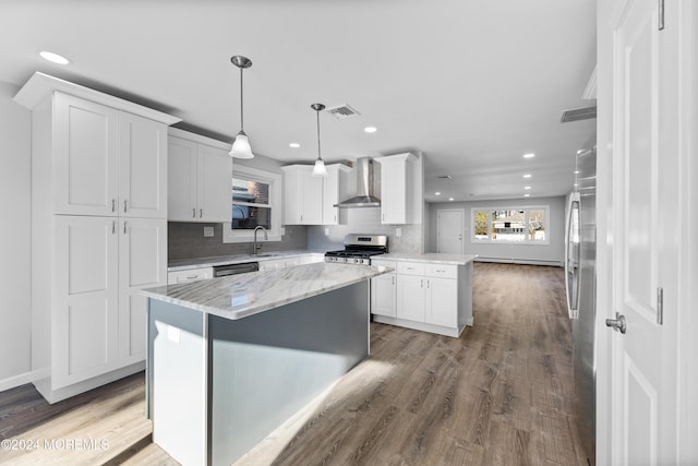 kitchen with white cabinetry, sink, wall chimney exhaust hood, pendant lighting, and appliances with stainless steel finishes