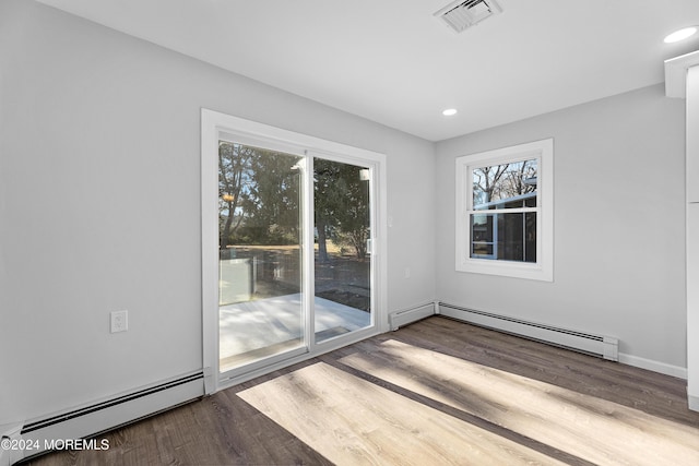 unfurnished room with hardwood / wood-style floors and a baseboard heating unit