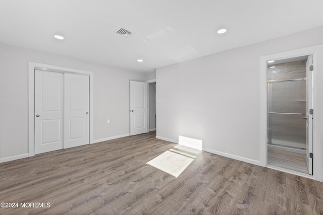 unfurnished bedroom featuring connected bathroom, light hardwood / wood-style flooring, and a closet