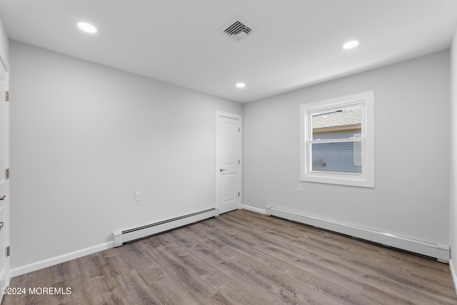 unfurnished room with a baseboard radiator and light wood-type flooring