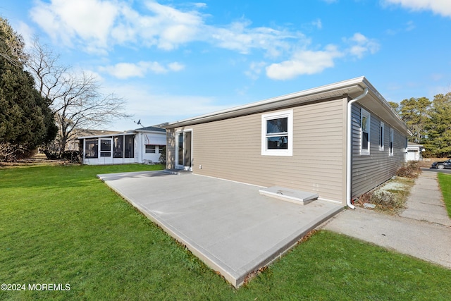 rear view of property featuring a sunroom, a yard, and a patio