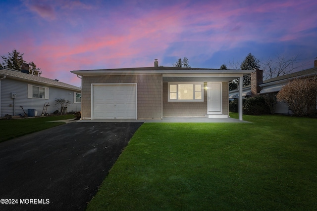 ranch-style house featuring a garage and a lawn