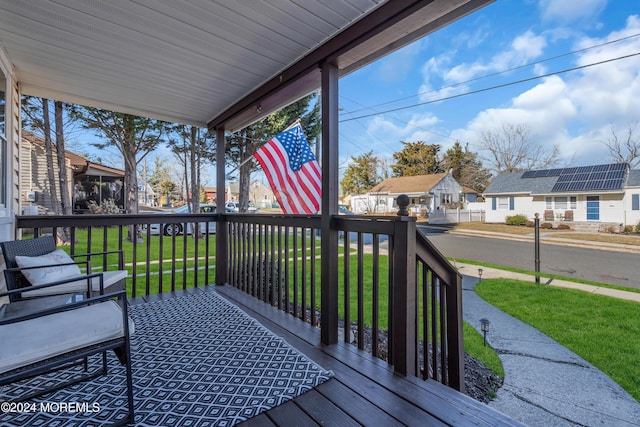 deck featuring covered porch and a lawn