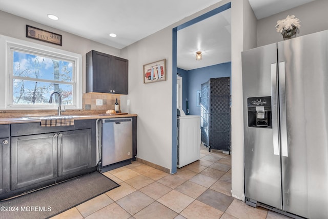 kitchen with appliances with stainless steel finishes, tasteful backsplash, dark brown cabinetry, sink, and light tile patterned floors