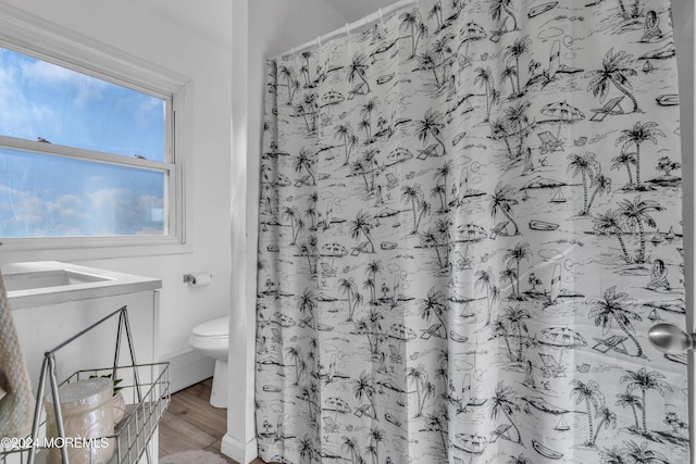 bathroom featuring hardwood / wood-style floors, toilet, and curtained shower