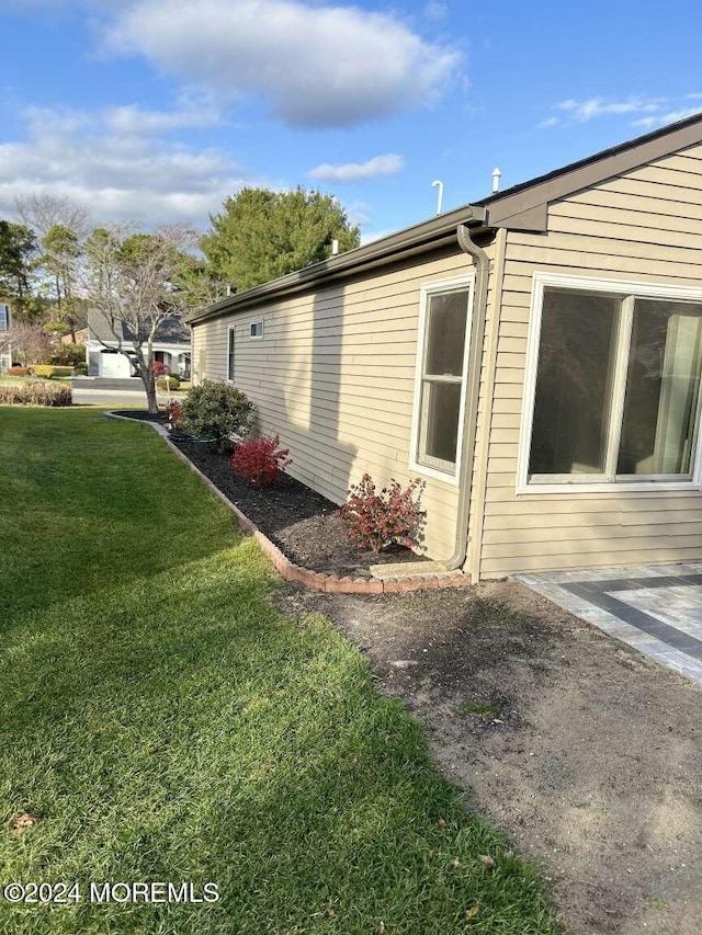 view of property exterior with a lawn and a patio area