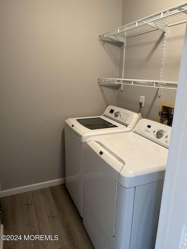 clothes washing area featuring washer and clothes dryer and dark hardwood / wood-style flooring