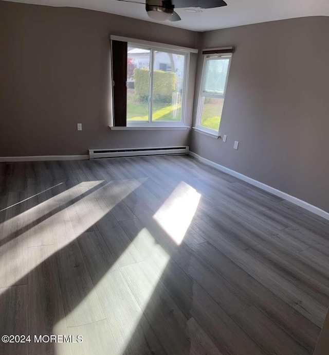 unfurnished room featuring ceiling fan, dark hardwood / wood-style flooring, and a baseboard heating unit