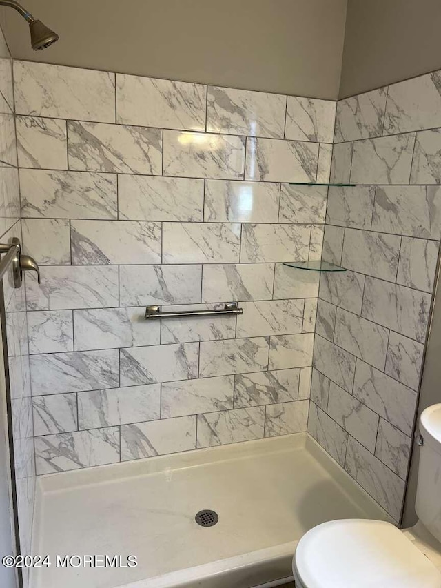 bathroom with tiled shower and toilet