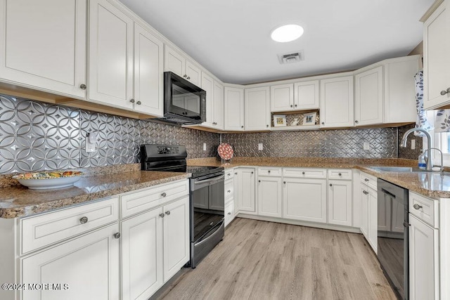 kitchen featuring black appliances, white cabinets, sink, light hardwood / wood-style flooring, and stone countertops