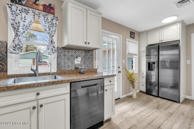 kitchen with sink, appliances with stainless steel finishes, tasteful backsplash, light hardwood / wood-style floors, and white cabinetry