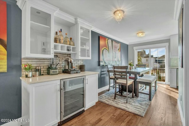 bar featuring decorative backsplash, light hardwood / wood-style floors, white cabinetry, and beverage cooler