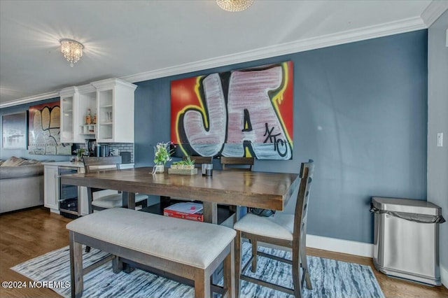 dining space featuring wood-type flooring, crown molding, beverage cooler, and a chandelier