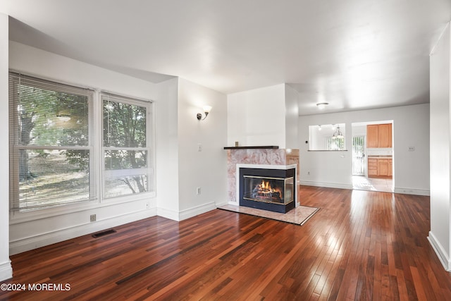 unfurnished living room featuring a multi sided fireplace and wood-type flooring