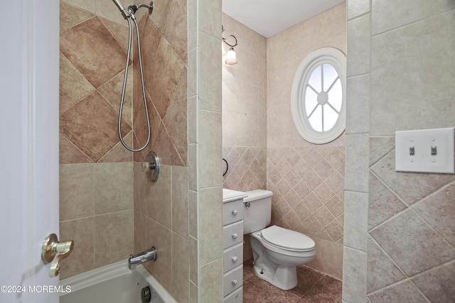 full bathroom with vanity, toilet, tiled shower / bath, and tile walls