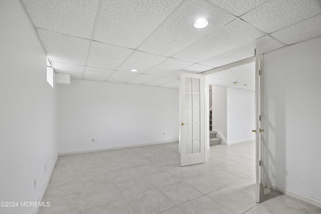 basement featuring french doors and a paneled ceiling