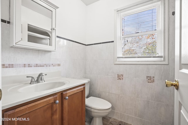 bathroom featuring vanity, toilet, and tile walls