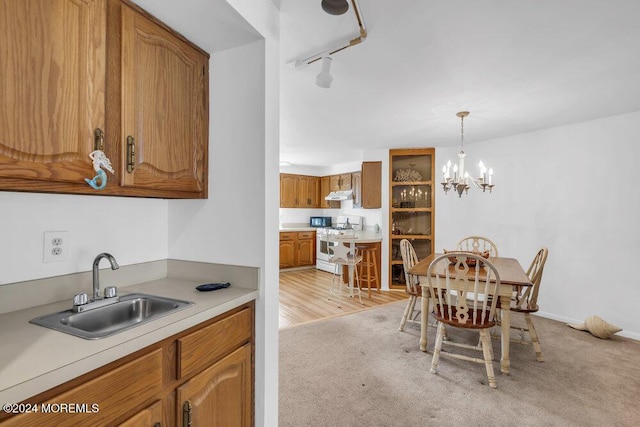 kitchen featuring light carpet, an inviting chandelier, white range, sink, and decorative light fixtures