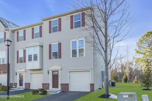 view of property with a garage, central air condition unit, and a front yard