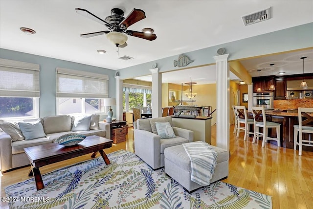 living room with ceiling fan, light hardwood / wood-style floors, and ornate columns