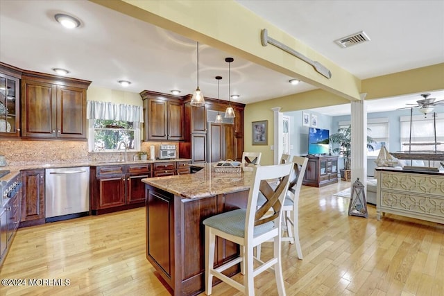 kitchen featuring dishwasher, a kitchen breakfast bar, tasteful backsplash, pendant lighting, and a kitchen island