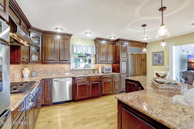 kitchen with sink, decorative backsplash, light stone countertops, decorative light fixtures, and stainless steel appliances