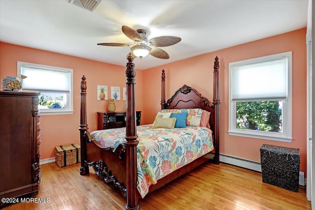 bedroom with light wood-type flooring, baseboard heating, and ceiling fan