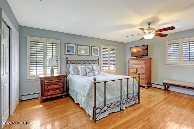 bedroom with ceiling fan, light hardwood / wood-style floors, baseboard heating, and a closet