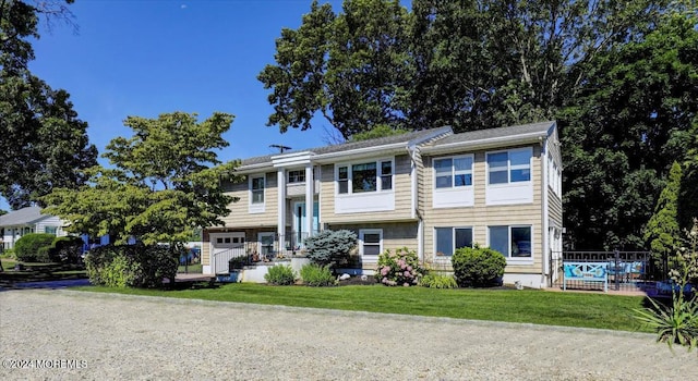 raised ranch featuring a front lawn and a garage