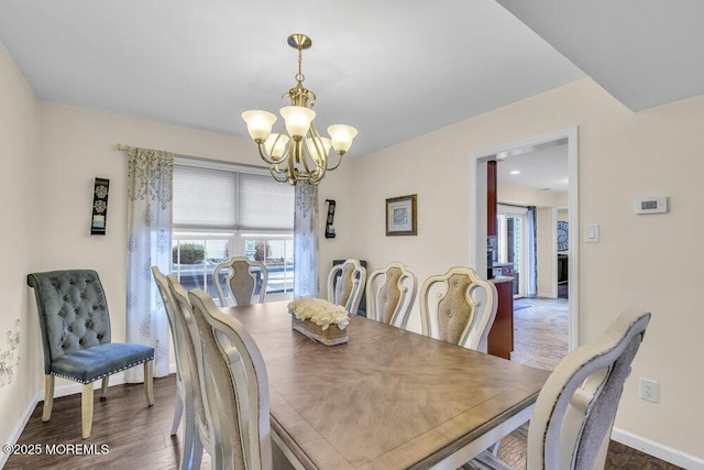 dining space with dark hardwood / wood-style floors, a wealth of natural light, and a notable chandelier