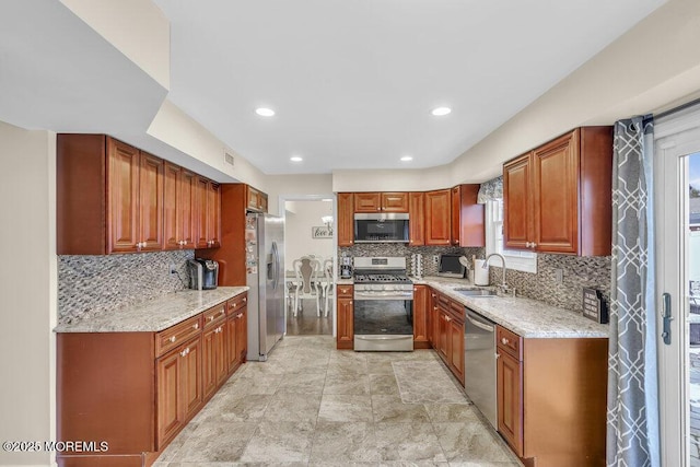 kitchen featuring backsplash, light stone countertops, sink, and appliances with stainless steel finishes