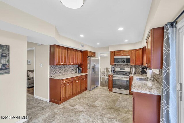 kitchen with tasteful backsplash, light stone countertops, sink, and stainless steel appliances