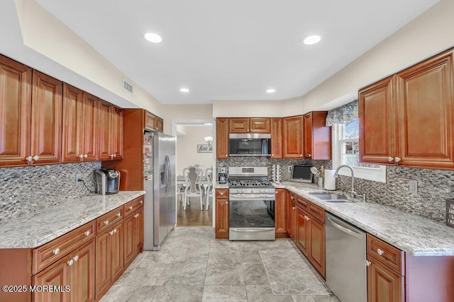 kitchen featuring decorative backsplash, light stone counters, sink, and stainless steel appliances