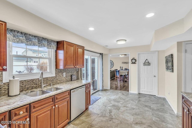 kitchen featuring backsplash, dishwasher, light stone countertops, and sink