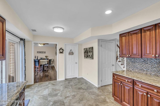 kitchen with ceiling fan, decorative backsplash, and light stone countertops