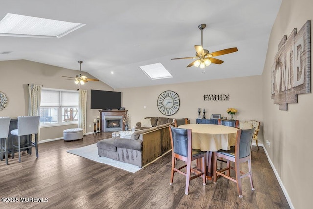 dining area featuring dark hardwood / wood-style floors, lofted ceiling with skylight, and ceiling fan