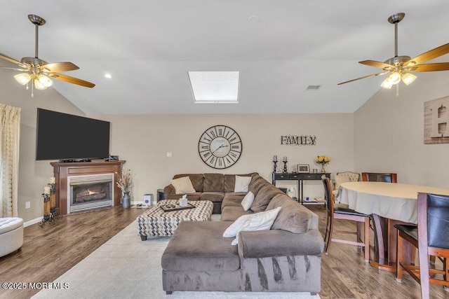 living room with hardwood / wood-style floors, lofted ceiling with skylight, and ceiling fan