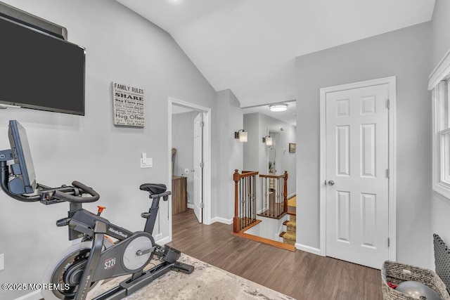 exercise room with dark wood-type flooring and vaulted ceiling