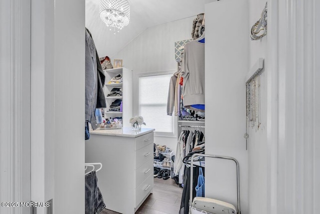 spacious closet with a notable chandelier and lofted ceiling