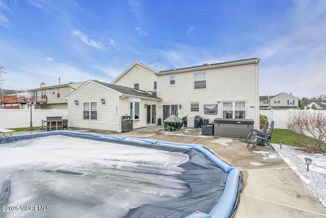 rear view of property with cooling unit and a hot tub