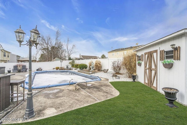 view of swimming pool featuring a lawn, a patio, and a storage shed