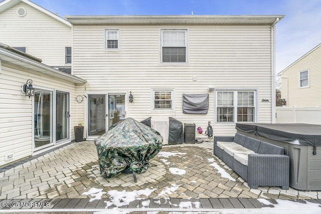 rear view of property with outdoor lounge area, a hot tub, and a patio area