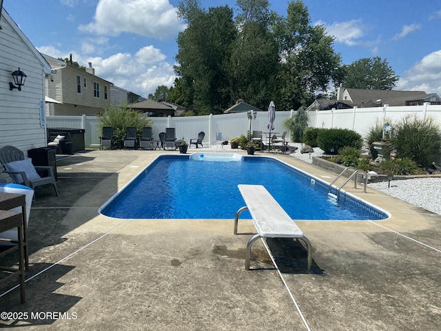 view of swimming pool with a patio area and a diving board